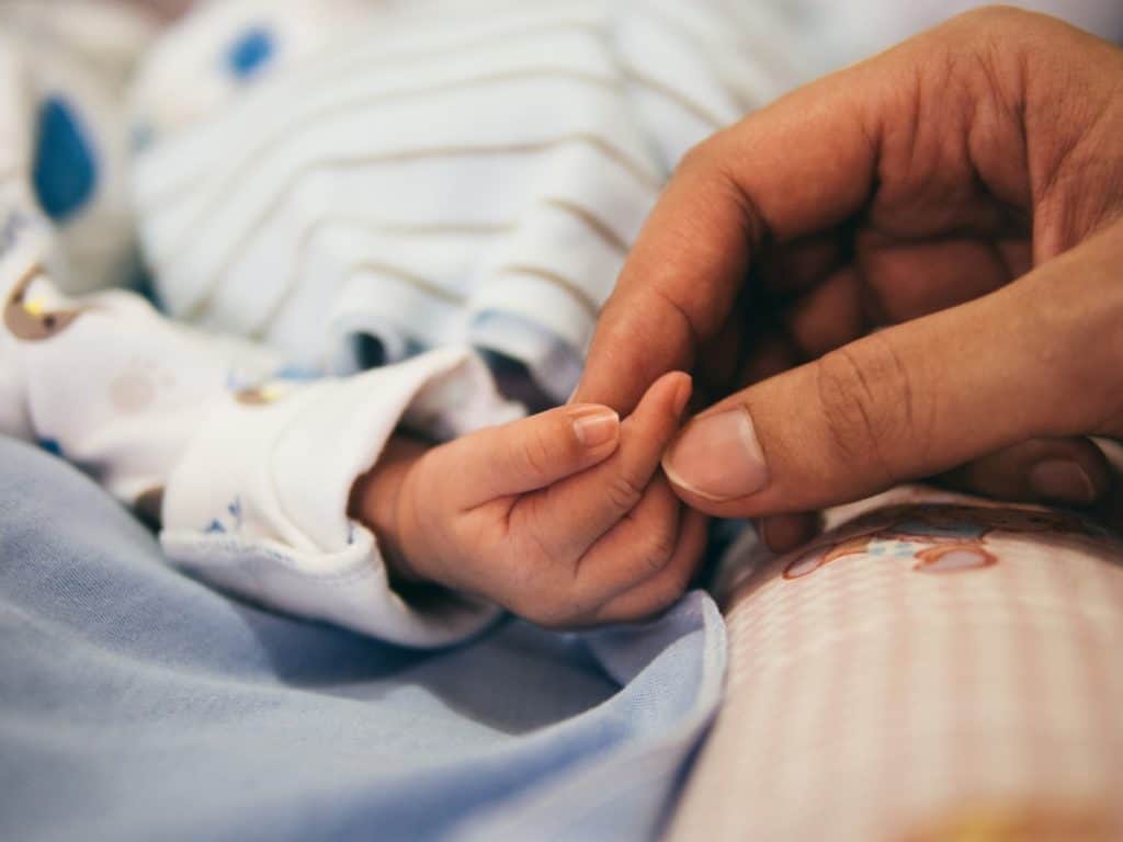 parent holding tiny baby hand while sleeping